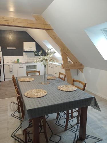 une table de salle à manger avec des chaises et une cuisine dans l'établissement appart 2 chambres, à Noyen-sur-Sarthe