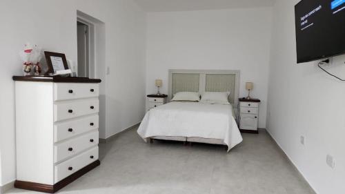 a white bedroom with a bed and a dresser at Departamento muy confortable (monoambiente) 2 personas in Viedma