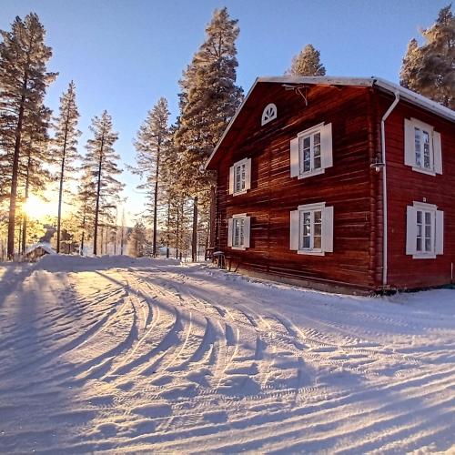 ein Holzhaus im Schnee mit einer Feldstraße in der Unterkunft Midgård in Jörn