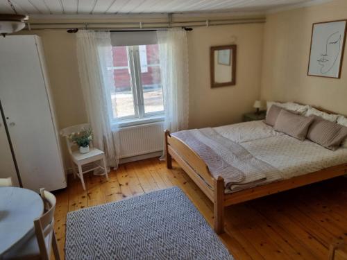 Schlafzimmer mit einem Bett, einem Tisch und einem Fenster in der Unterkunft Midgård in Jörn