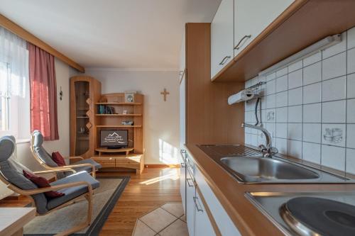 a kitchen with a sink and a living room at Apartmenthaus - Erlebenswert Bauernhof Gruber in Sankt Lorenzen im Lesachtal