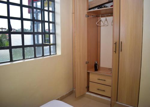 ein Schlafzimmer mit einem Schrank und einem Fenster in der Unterkunft Faisha 1bedroom Near Sarova Woodlands in Nakuru