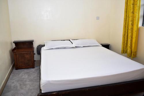 um quarto com uma cama branca e uma mesa de madeira em Faisha 1bedroom Near Sarova Woodlands em Nakuru