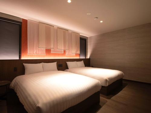two beds in a hotel room with two bedsskirts at Rakuten STAY VILLA Nikko in Nikko