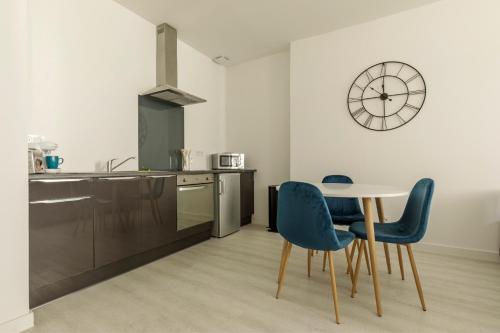 une cuisine avec une table, des chaises et une horloge dans l'établissement LE BLEU - Lumineux, 1 chambre, salle de bain moderne, à Castelsarrasin