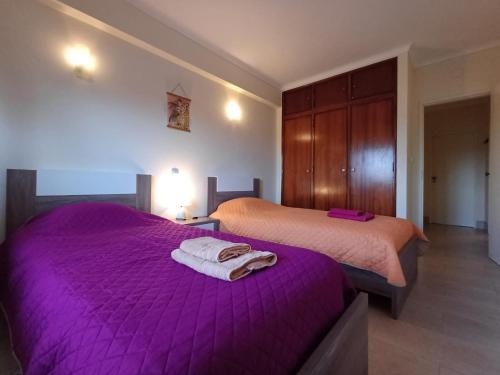 a bedroom with two beds with purple sheets and towels at Apartment Amalia in Albufeira