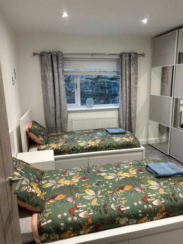 a bedroom with two beds and a window at Garreg Fawr Trearddur Bay - Ty Melyn in Trearddur