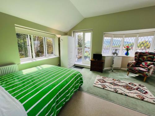 a bedroom with a bed and a chair and windows at Pentre Cerrig Country House in Llanferres