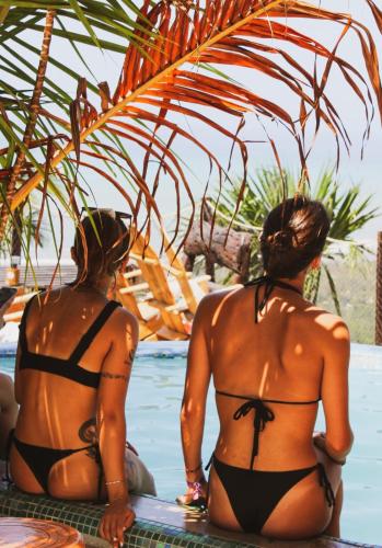 two women in bathing suits sitting in the water at Puerto Alto Hostel in Santa Marta