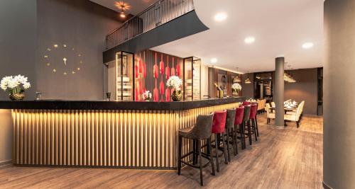 a bar with a row of stools in a restaurant at PLAZA INN Mühldorf in Mühldorf