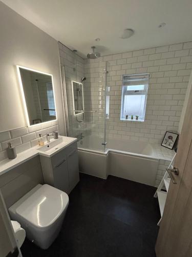 Garreg Fawr Trearddur Bay - Ty Melyn في تريرددور: حمام مع مرحاض وحوض استحمام ومغسلة