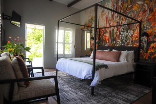 a bedroom with a canopy bed with a painting on the wall at Hemel 'N Aarde Stud in Hermanus