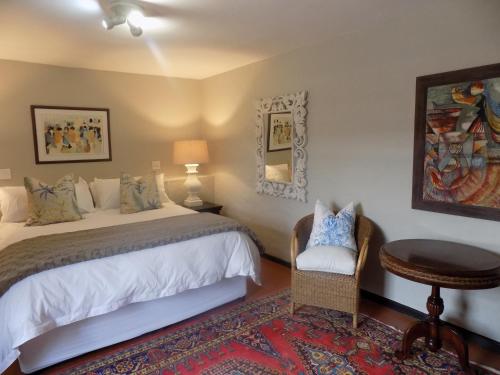 a bedroom with a bed and a table and a chair at Barrydale Karoo Lodge - Boutique Hotel in Barrydale