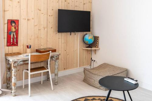 a room with a desk and a television on a wall at Le ciel, le soleil et la mer in Narbonne