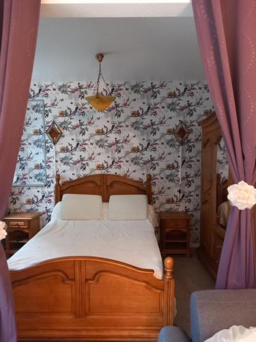 1 dormitorio con 1 cama y papel pintado con motivos florales en Les Églantines, en Luxeuil-les-Bains