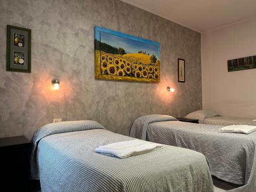 una stanza con tre letti e un dipinto di un girasole di Albergo Roma a Valdagno