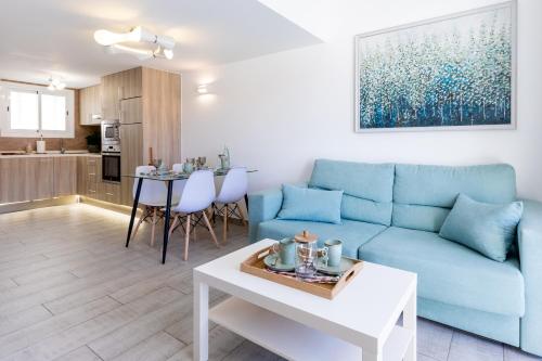 ein Wohnzimmer mit einem blauen Sofa und einem Tisch in der Unterkunft Luxury Parque Santiago I in Playa de las Americas