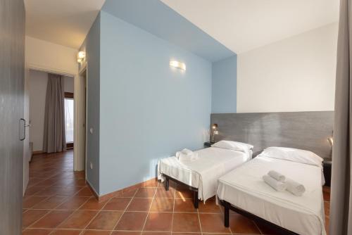 two beds in a room with blue walls and tile floors at Residence Le Rocce Rosse in Isola Rossa