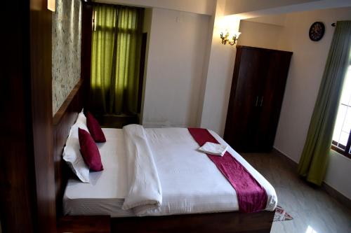 a bedroom with a bed with white sheets and red pillows at LILY GUEST HOUSE in Shillong