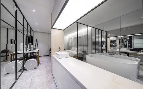 La salle de bains est pourvue d'une grande baignoire, d'un lavabo et d'une baignoire. dans l'établissement Cacao Hotel, à Incheon