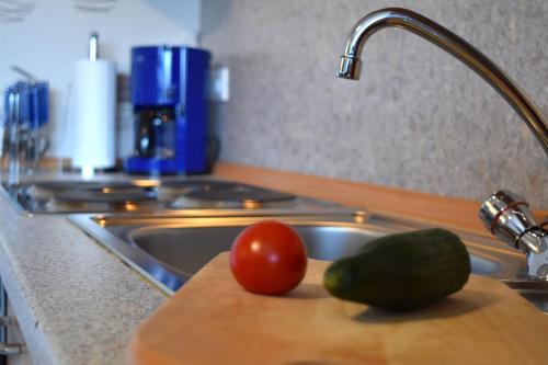 un fregadero con tomate y pepino en una tabla de cortar en Ferienwohnung Martina, en Medebach