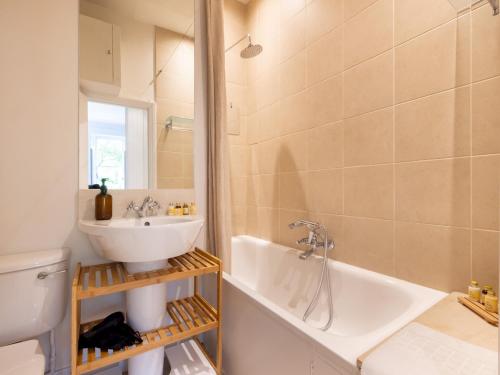 uma casa de banho com um lavatório, uma banheira e um WC. em Pass the Keys Sophisticated Studio in South Kensington em Londres