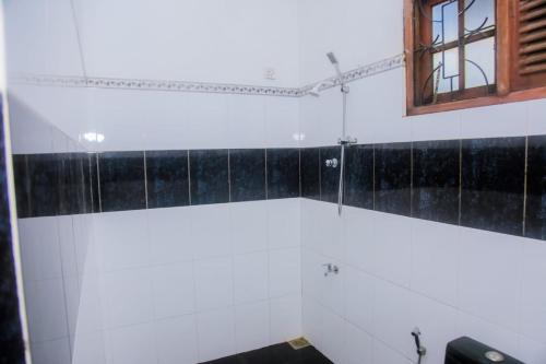baño con paredes blancas y azulejos negros en Seyoo Villa en Ahangama