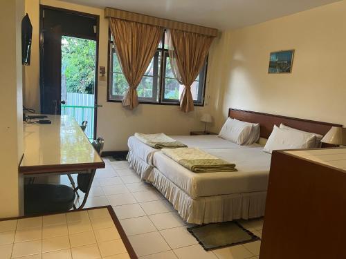 Habitación de hotel con 2 camas y escritorio en โรงแรม พรรณทวี en Nong Khai