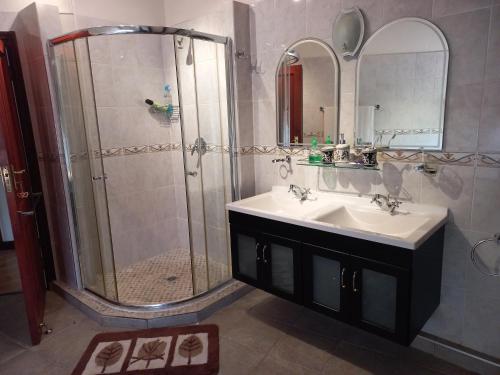 W łazience znajduje się prysznic, umywalka i lustro. w obiekcie Forest Dream House w mieście Kloof