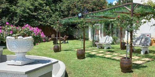 a garden with benches and a pergola with flowers at Forest Dream House in Kloof