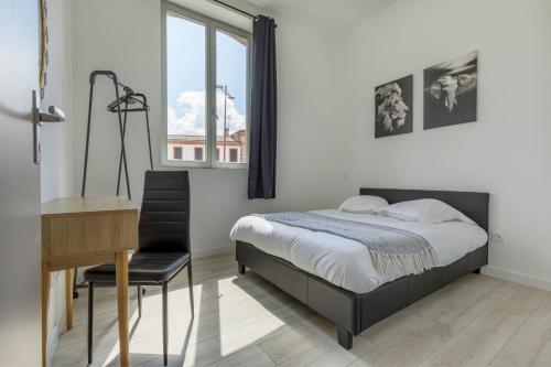 1 dormitorio con cama, escritorio y ventana en LE SICRE - T3 confort, centre Castelsarrasin, parking, en Castelsarrasin
