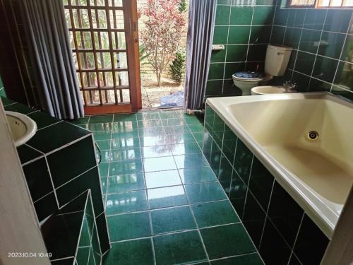 a bathroom with a tub and a green tiled floor at GREEN TREE in Mtubatuba