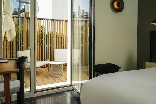 ein Schlafzimmer mit einem Balkon, einem Bett und einem Schreibtisch in der Unterkunft Nobu Hotel Sevilla in Sevilla