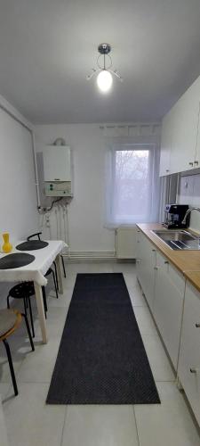 cocina con armarios blancos, mesa y ventana en Apart´ Coco, en Luduş