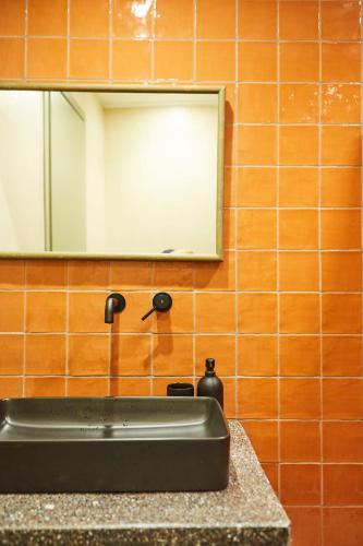 a bathroom sink with a faucet and a mirror at Mosaics Athens Boutique Apartments in Athens