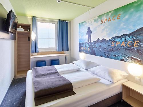 a bedroom with a bed with a poster on the wall at B&B Hotel Köln-Airport in Cologne