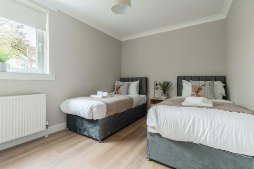 a bedroom with two beds and a window at Shaw Apartment in Glasgow