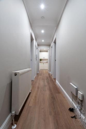an empty hallway with white walls and wood floors at Shaw Apartment in Glasgow