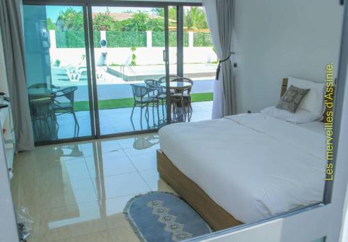 a bedroom with a bed and a view of a patio at Les merveilles d’assinie in Assinie