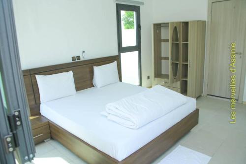 a bedroom with a large bed with white sheets at Les merveilles d’assinie in Assinie