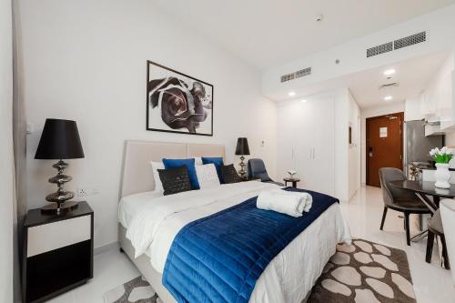 a bedroom with a large bed and a dining room at Cozy studio at DamacHills2 in Dubai