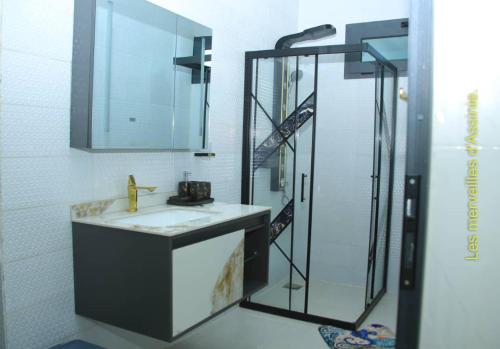 a bathroom with a sink and a shower with a mirror at Les merveilles d’assinie in Assinie