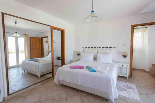 a white bedroom with two beds and a mirror at Luxury Private Family Villa with Private Infinity pool in Parikia