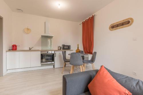 un salon avec un canapé et une table et une cuisine dans l'établissement LE CORAIL - 1 chambre, idéal couple, parking, 10min Canal du Midi, à Castelsarrasin