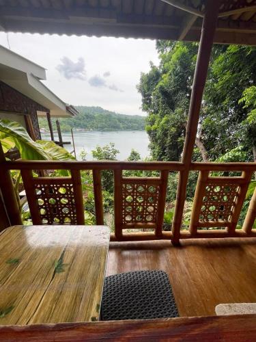 a porch with a table and a view of a river at Camiguin Blue Lagoon Cottages in Mahinog
