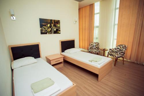 una habitación de hotel con 2 camas y una silla en Göygöl Olimpiya İdman Kompleksi en Xanlar