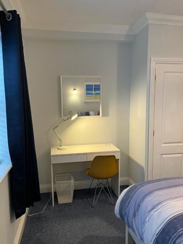 a bedroom with a desk with a lamp and a bed at Rockmount Court in Bournemouth