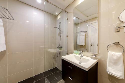 Baño blanco con lavabo y espejo en Cozy studio at DamacHills2 en Dubái