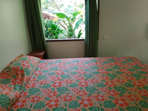 Vaïare的住宿－Fare Mihimana，一间卧室配有一张带花卉床罩的床和窗户。