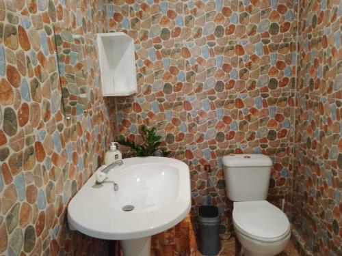 La salle de bains est pourvue de toilettes blanches et d'un lavabo. dans l'établissement Fare Mihimana, à Vaïare